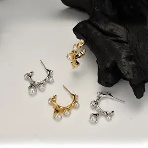 Detail of C-shaped hoop earrings in gold and silver finish with small white pearls