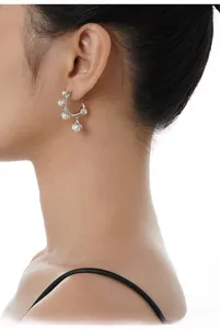 Close-up of a silver flower-shaped earring with pearls on a model's ear