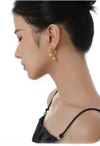 Detail of gold C-shaped earrings with pearls on a model, featuring liquid metal design