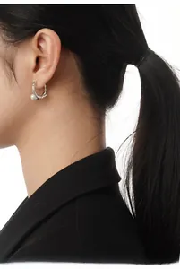 Detail shot of silver twist textured hoop earring with white pearl on model's ear