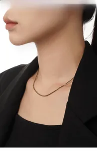Close-up of minimalist S925 sterling silver gold cauliflower chain worn over black fabric