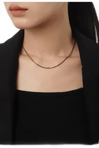 Detail shot of vintage gold chain necklace on model wearing a black blazer jacket
