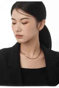 Close-up of minimalist antique gold chain necklace on model wearing a black blazer