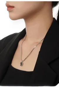 Dettaglio della catena in argento S925 con ciondolo in conchiglia su giacca da completo nera