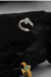 Detailed view of textured S925 silver and gold rings featuring radiant oval opal stones