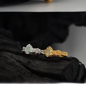 Macro shot of silver and gold rings with irregular lava texture and teardrop opal stones