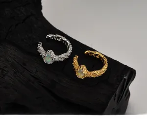 Macro shot of silver and gold textured lava ear cuffs with teardrop opal stones