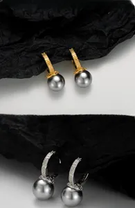 Macro shot of S925 silver earrings with intricate vine patterns and grey shell pearls