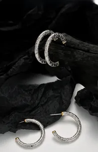Détail de boucles d'oreilles C en argent S925 avec motif en relief et pointes dorées