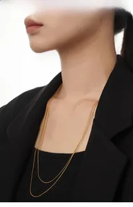Close-up of double-layer gold snake bone chain necklace worn on a black jacket