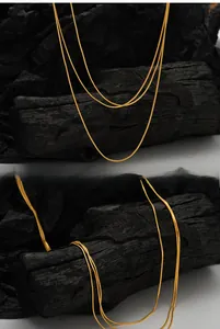Detailed close-up of a sleek golden snake bone chain necklace on black texture