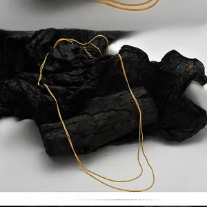 Close-up of double layered gold snake chain necklace on a black textured background