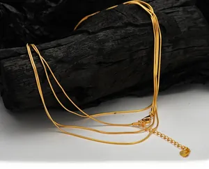 Detailed view of layered gold snake chain necklace on a charcoal prop with lobster clasp