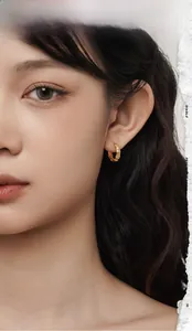 Detail of 18K gold bamboo style small hoop earring with sparkling micro diamonds on model