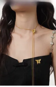 Detail of elegant gold butterfly pendant necklace worn over black sweater