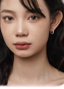 Close-up of small silver hoop earring with bamboo texture on female model's ear