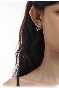 Détail macro de boucles d'oreilles papillon en argent liquide et nacre sur un mannequin