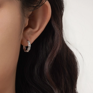 Elegant silver bamboo joint hoop earrings with shimmering crystals on a female model