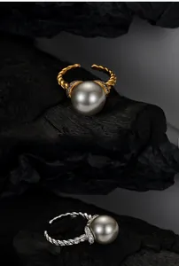 Macro detail of intertwined S925 silver pearl rings with pavé diamonds and twisted band