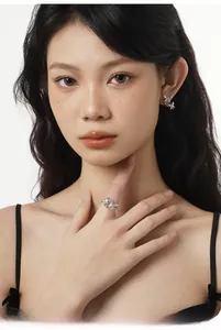 Gros plan d'un mannequin portant des boucles d'oreilles papillon et une bague en nacre