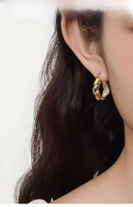 Close-up of S925 sterling silver two-tone twisted Mobius hoop earrings on model