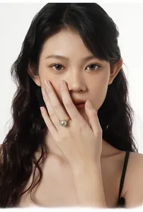 Detail of a gold rope band pearl ring with tiny diamonds worn by a model