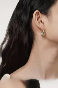 Close-up of S925 sterling silver two-tone Mobius earrings on a female model