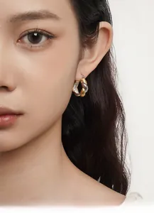 Close-up of a model wearing two-tone silver and gold Mobius twist hoop earrings