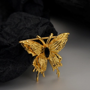 Gestructureerde gouden vlinderbroche met zwarte edelsteen in vloeibaar metaalstijl