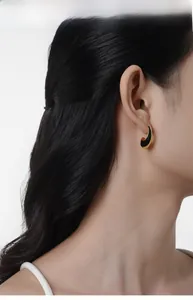 Detail view of crescent moon stud earrings with black enamel and gold plating on model