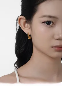 Close-up of elegant gold streamlined hoop earrings worn on model for a modern look