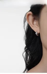 Close-up of S925 sterling silver bow earrings with zircons on a model's ear