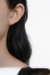 Gros plan de boucles d'oreilles fleur en or avec zircons pavés sur l'oreille d'un mannequin