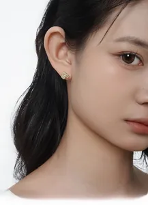 Gros plan de boucles d'oreilles fleurs en zircone portées sur l'oreille d'un modèle