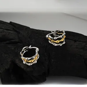 Macro detail of S925 sterling silver hoop earrings with irregular two-tone gold plating