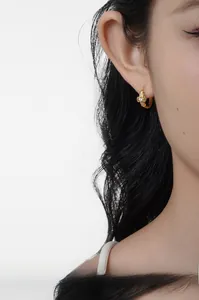 Close-up of gold-plated silver bow hoop earrings with sparkling zircon on a model