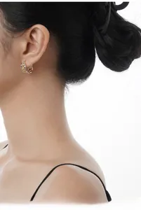 Detail of irregular hollow geometric silver and gold earrings worn by a model