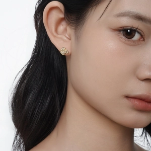 Élégantes boucles d'oreilles camélia dorées avec zircons portées par une femme