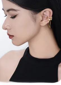 Detail of gold double-layer ear cuff with zircon inlay and elegant long chain tassels