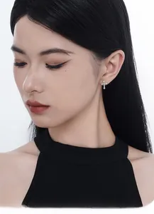 Close-up of S925 silver cross stud earrings with sparkling cubic zirconia on a model