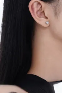 Gros plan d'une boucle d'oreille en zircone étincelante portée sur l'oreille avec monture argent