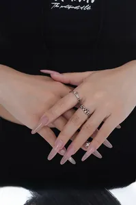 Close-up of S925 sterling silver rings with red gems on hand with long pink nails