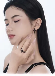Gothic matte black cross jewelry set with red gems worn by a model in a close-up shot