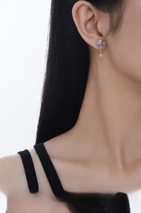 Detail of S925 silver cross stud earring with light blue gem on female ear