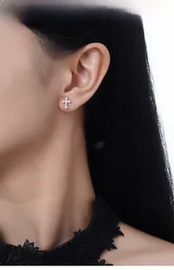 Macro side view of a model wearing the small S925 silver cross stud earring with zircons
