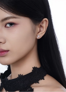 Close-up of a model wearing sparkling S925 sterling silver cross stud earrings with zircons