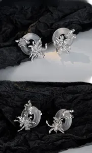 Detail of silver spider crawling on translucent ring earrings with artistic design