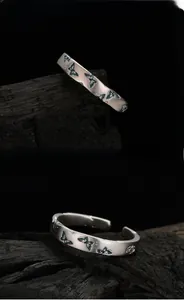Detail of silver butterfly ring with teal enamel wings on a textured dark background