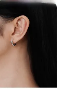 Détail de boucles d'oreilles créoles en argent S925 avec étoiles sur le mannequin