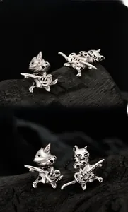 Detailed close-up of S925 sterling silver cat playing guitar earrings on a black wood base